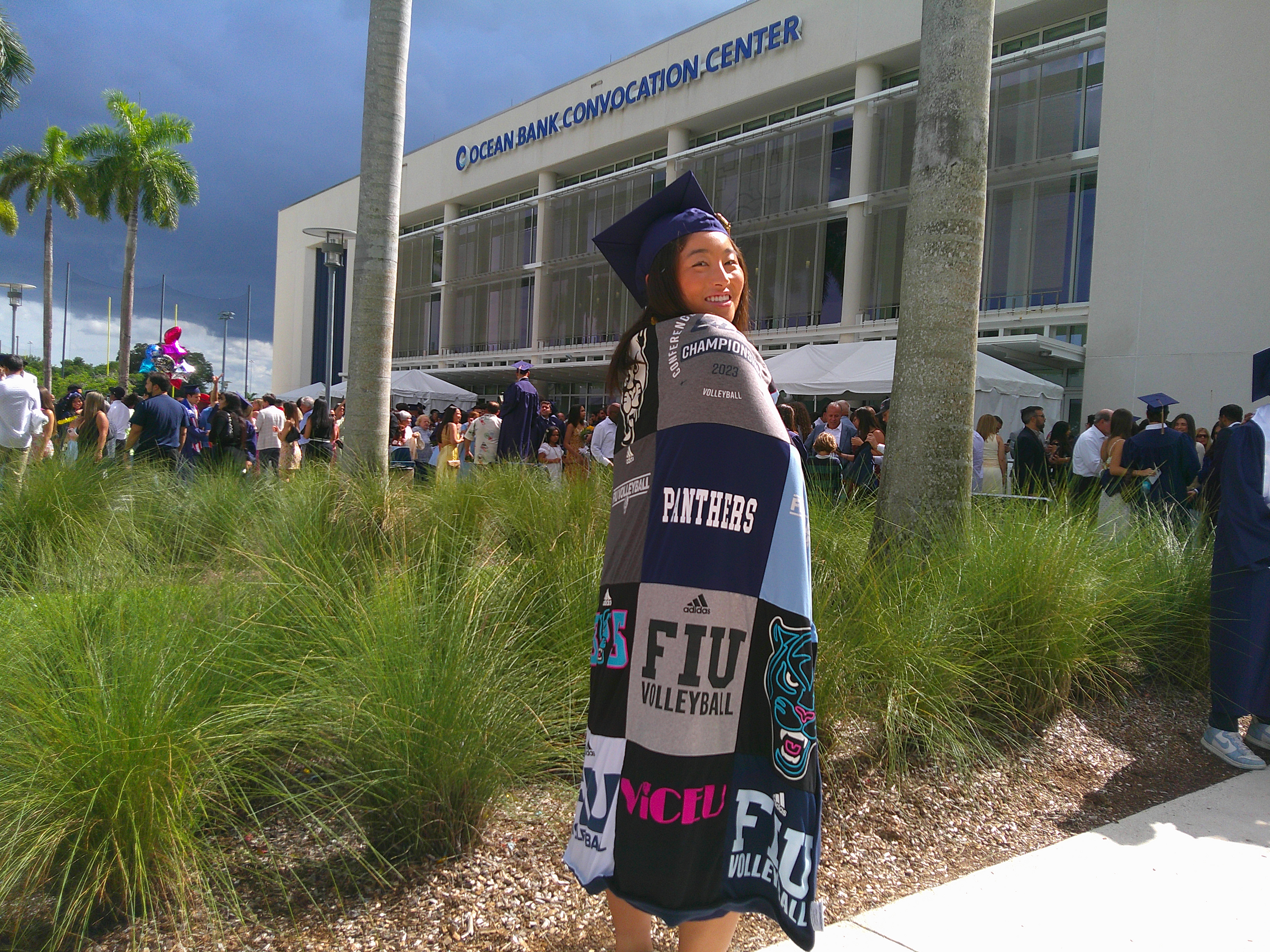 College graduate celebrating at university graduation ceremony with family